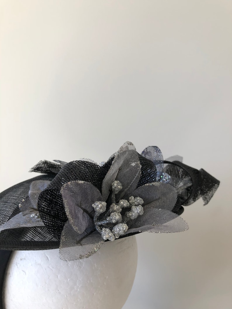 New black saucer fascinator with silver flowers and black loops on a headband!