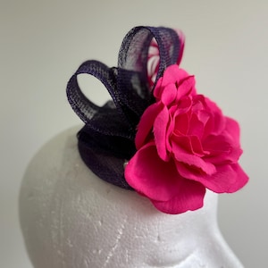 Purple flowered fascinator on a pink base with loops and feathers!