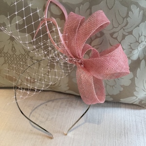 May include: A pink headband with a pink bow and a white veil. The headband is made of metal and has a delicate design.