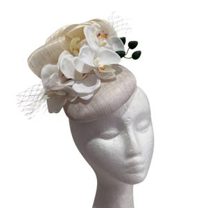 White round fascinator with orchids and silk abaca loops.