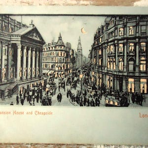 May include: Vintage postcard depicting Mansion House and Cheapside in London. The black and white illustration shows a bustling street scene with buildings, horse-drawn carriages, and pedestrians. The text "Mansion House and Cheapside" and "London" are visible.
