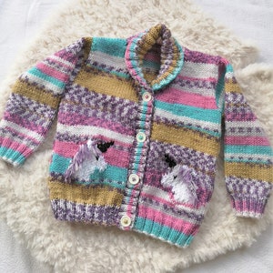 May include: A striped cardigan with a button closure and unicorn appliques. The cardigan is made in a variety of colors, including pink, purple, teal, and gold.