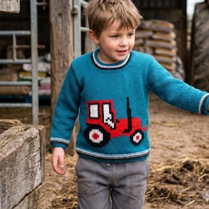 May include: A teal blue sweater with a red tractor design. The sweater has a crew neck with black and white stripes and matching stripes on the cuffs. The child is wearing gray pants.