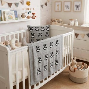 May include: A white crib with a gray panda-patterned blanket and pillow. The nursery is decorated with a mobile, framed animal prints, and a woven basket with toys. A shelf holds books and decorative plush toys.