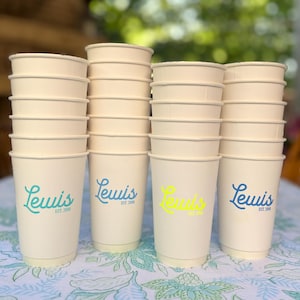May include: A stack of 12 white paper cups with a blue and yellow logo that says "Lewis Est. 2008".