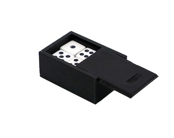 Puede incluir: Una caja negra con una tapa con bisagras, que contiene cuatro dados blancos con puntos negros. La caja está hecha de un material texturizado y tiene una pequeña etiqueta rectangular en la tapa.