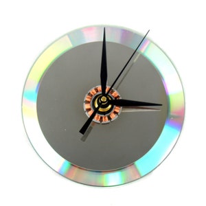 May include: A clock made from a repurposed CD with black hands and a silver face. The clock has a rainbow iridescent border.