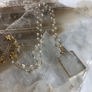 May include: A gold chain necklace with clear crystal beads and a large, rectangular, white gemstone pendant.