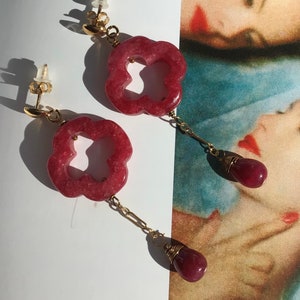 Puede incluir: Un par de pendientes de oro con colgantes de color rosa en forma de flor y piedras de color rosa en forma de lágrima.