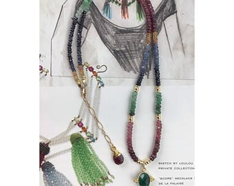 May include: A multi-strand necklace with colorful gemstone beads in shades of blue, green, pink, and purple. The necklace features a gold pendant with a green gemstone and a gold chain with a red gemstone. The image includes text that reads "SKETCH BY LOULOU PRIVATE COLLECTION".