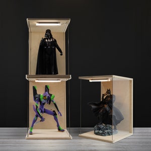 Puede incluir: Tres vitrinas de madera con laterales de cristal transparente e iluminación LED. Cada vitrina alberga una figura de acción diferente: Darth Vader, un Evangelion Unit-01 y Batman. Las vitrinas tienen un acabado de madera natural.