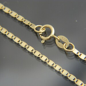 May include: Close-up of a gold necklace with a delicate, flat link chain design. The necklace features a lobster clasp closure and a small tag with the marking "14KT". The chain is approximately 45 cm long.