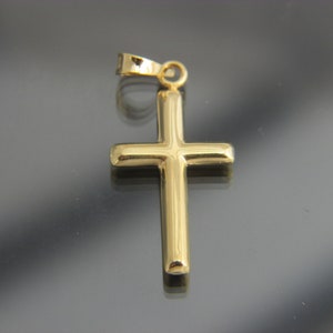 May include: A gold-colored cross pendant with a simple design. The pendant has a loop at the top for attaching to a chain.