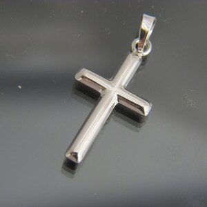 May include: A silver cross pendant with a simple design.