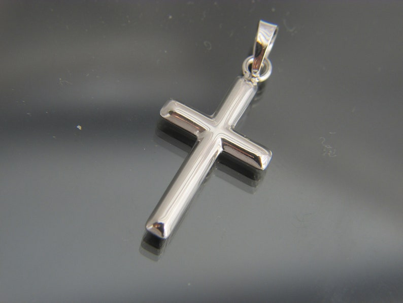 May include: A silver cross pendant with a simple design.