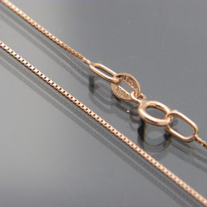 May include: A rose gold chain necklace with a box clasp. The chain is made of small, square links.