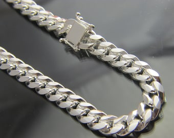 Puede incluir: Un collar de cadena de plata con un cierre seguro. Los eslabones de la cadena son gruesos y entrelazados, reflejando la luz. El cierre es rectangular y está bien sujeto. Esta joya es adecuada para diversas ocasiones.