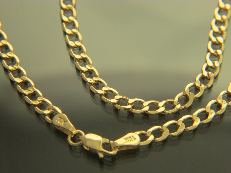 K&ouml;nnte beinhalten: Eine goldene Halskette mit einem Curb-Kettenglied-Design. Die Kette ist aus 10 Karat Gold gefertigt und hat einen Karabinerverschluss.