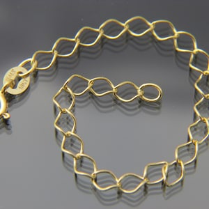 May include: A gold chain bracelet with a lobster clasp. The chain is made of small, linked, oval-shaped pieces. The clasp has a tag that reads "10K".