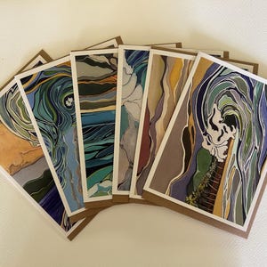 May include: A set of six rectangular greeting cards arranged in a fan shape. Each card features a unique, colorful illustration with flowing, organic lines and abstract patterns in shades of blue, green, yellow, brown, and white.