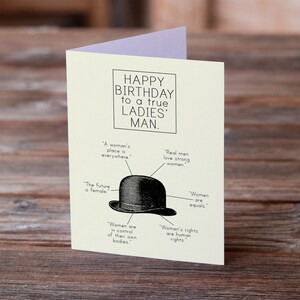 Könnte beinhalten: Eine Karte mit einer Schwarzweißillustration eines Bowlers. Der Text auf der Karte lautet "Happy Birthday to a true Ladies' Man." Der Text um den Hut herum lautet "Der Platz einer Frau ist überall." "Echte Männer lieben starke Frauen." "Die Zukunft ist weiblich." "Frauen sind gleich." "Frauen kontrollieren ihre eigenen Körper." "Frauenrechte sind Menschenrechte."