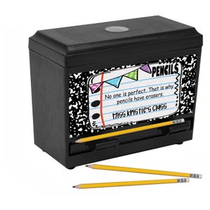 May include: A black pencil sharpener with a wood-grain texture. The front features a notebook paper design with the word "PENCILS" and the text "No one is perfect. That is why pencils have erasers. Miss Kristie's Class." Three yellow pencils are in front.