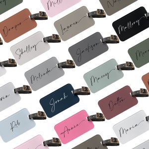 May include: A collection of luggage tags with various names written in cursive on them. The tags are made of different colors and materials, including brown, gray, black, blue, pink, and green.