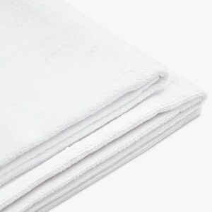 May include: A white, soft, and fluffy towel folded in thirds. The towel is made of a plush material and is perfect for drying off after a bath or shower.