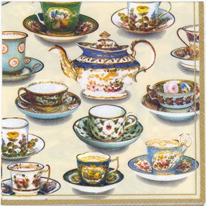 May include: A decorative paper napkin featuring a collection of vintage teacups, saucers, and a teapot. The teacups and teapot are adorned with floral patterns, gold accents, and various colors, including blue, green, and pink, set against a cream background.