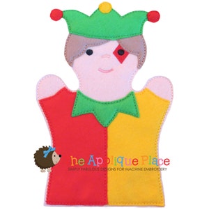 Puede incluir: Una marioneta de fieltro con forma de bufón, con una corona verde y un rombo rojo en la cara. El cuerpo de la marioneta está dividido en secciones rojas y amarillas. Un pequeño erizo con un lazo azul está en el lado izquierdo.