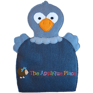 May include: A gray felt bird puppet with a large orange beak and white eyes. The puppet has a blue felt body with a white felt ruffle around the neck. The text "The Applique Place" is embroidered on the body of the puppet.