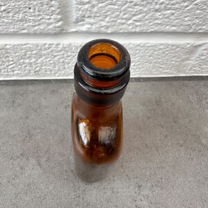 May include: Close-up of the top of a brown glass bottle with a wide mouth.