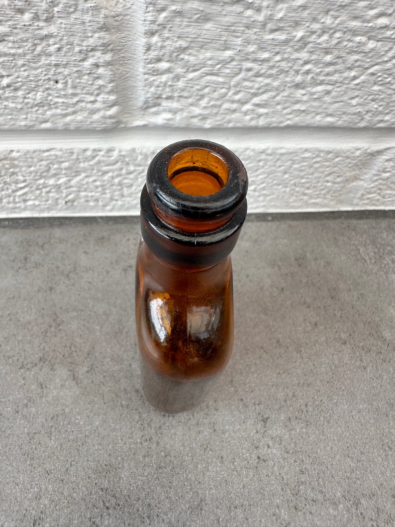 May include: Close-up of the top of a brown glass bottle with a wide mouth.