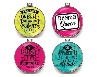 May include: Four round, metal pendants with humorous phrases. One says "I'll get over it but I need to be dramatic first." Another says "Drama Queen." The others say "So apparently I'm dramatic" and "So apparently I have an attitude."