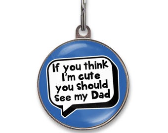 May include: A round blue pet ID tag with a silver metal border and a metal split ring at the top. The center features a white speech bubble graphic containing the black text: If you think I'm cute you should See my Dad, written in a bold font.