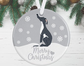 May include: A round, gray ceramic Christmas ornament featuring a dark gray and white dog sitting in the snow, looking upward. The design includes white snowflake patterns and the text Merry Christmas with a small heart icon, suspended by a white ribbon.