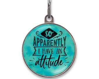 May include: A round metal pet ID tag with a silver-toned border and a split ring attachment. The center features a bright turquoise watercolor background with black text that reads: So apparently I have an attitude, styled in various fonts.