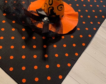 May include: Black table runner with orange polka dots and a witch hat with a black bow and veil.
