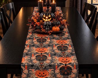May include: A rectangular table runner featuring a repeating pattern of orange jack-o'-lanterns, black skulls, spiders, and orange candles on a dark gray background. The runner is displayed on a black table with a centerpiece of pumpkins and candles.