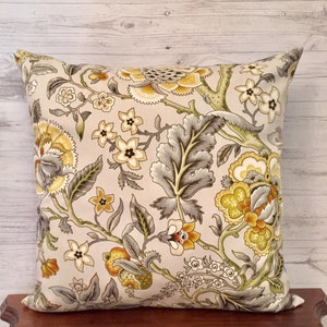 Puede incluir: Una almohada decorativa con un patr&oacute;n floral en tonos amarillos, verdes y grises. La almohada presenta un gran dise&ntilde;o floral con detalles intrincados.