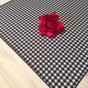 May include: Black and white checkered tablecloth with a red fabric flower in the center.