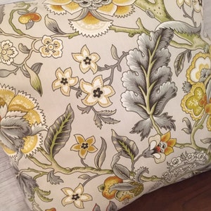 Puede incluir: Una almohada decorativa con un patr&oacute;n floral en tonos amarillos, verdes y grises. La almohada presenta un gran dise&ntilde;o floral con detalles intrincados y un fondo beige.