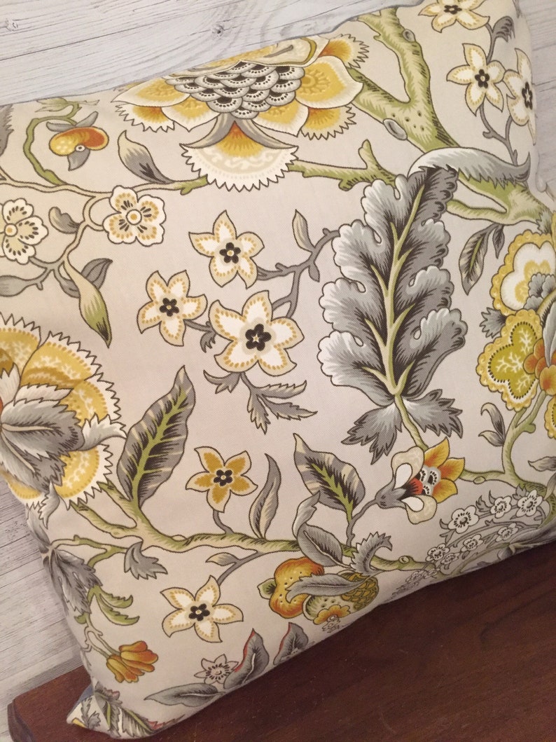 Puede incluir: Una almohada decorativa con un patr&oacute;n floral en tonos amarillos, verdes y grises. La almohada presenta un gran dise&ntilde;o floral con detalles intrincados y un fondo beige.