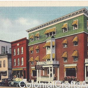 May include: A vintage postcard depicting the Belknap Hotel in Lakeport, New Hampshire. The hotel is a three-story brick building with a green roof and yellow awnings. The postcard features the text "Colonial Crafts Annex" and "Belknap Hotel Lakeport, N.H."