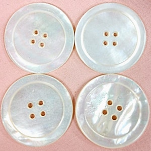 May include: Four white mother-of-pearl buttons with four holes each.