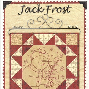 May include: A framed winter-themed quilt, 12 x 12 inches, featuring a snowman holding a sprig with a bird. The quilt has a red and cream color scheme with the words "Jack Frost" and "January" at the top. The bottom has a poem and the name "Kathy Schmitz".