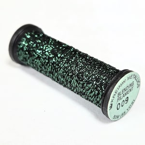 May include: A spool of metallic blending filament in a dark green color with a glittery effect. The spool has black ends and a label that reads "Kreink Metallics Blending Filament 009". The spool contains 50 yards of filament.