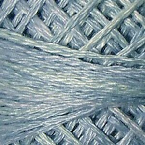 May include: Close-up of a skein of light blue yarn with a subtle shimmer. The yarn is tightly wound and has a smooth texture.