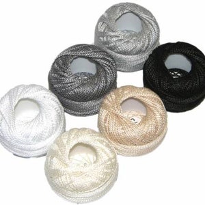May include: Six spools of embroidery floss in various colors, including white, gray, beige, and black. The spools are arranged in a circle.