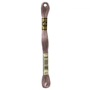 May include: A skein of DMC embroidery floss in color 451, a light brown shade. The floss is wrapped around a cardboard spool with a gold label that reads "DMC Mouliné Special 25 m 8.7 yds."